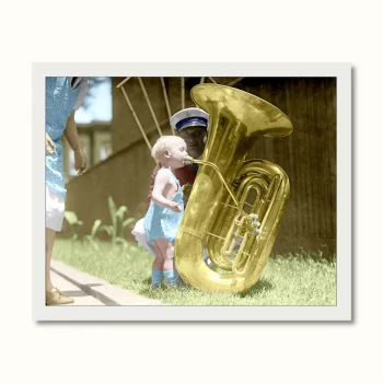 Un niño intentando hacer sonar una tuba en la calle